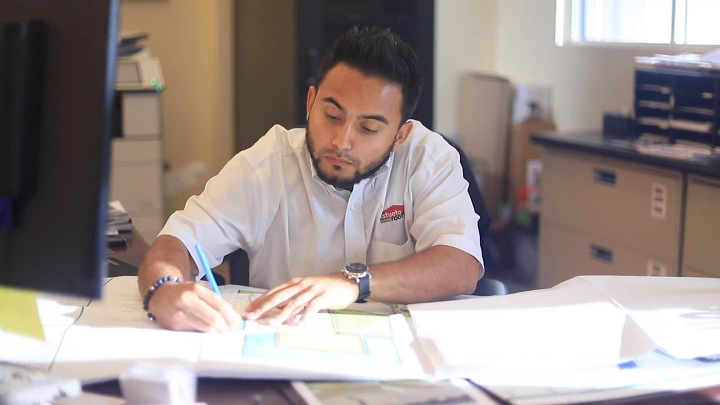 An Istueta Roofing team member reviewing project paperwork at the company office desk, where financing applications are prepared