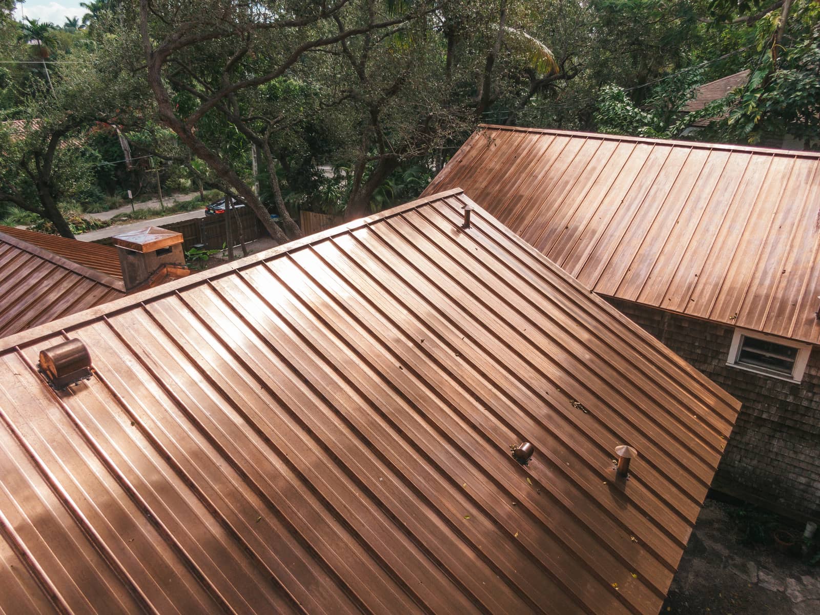 Aerial view of a Miami coastal home with a weathered copper roof near the shoreline