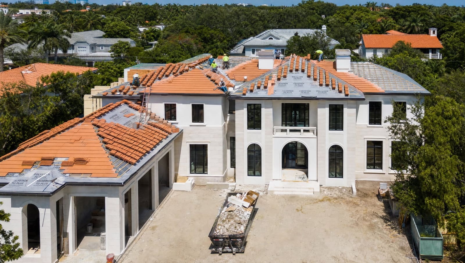 Luxury South Florida home with completed new construction roof in warm daylight, three-quarter elevation view showing subtropical landscaping and Coral Gables architectural character