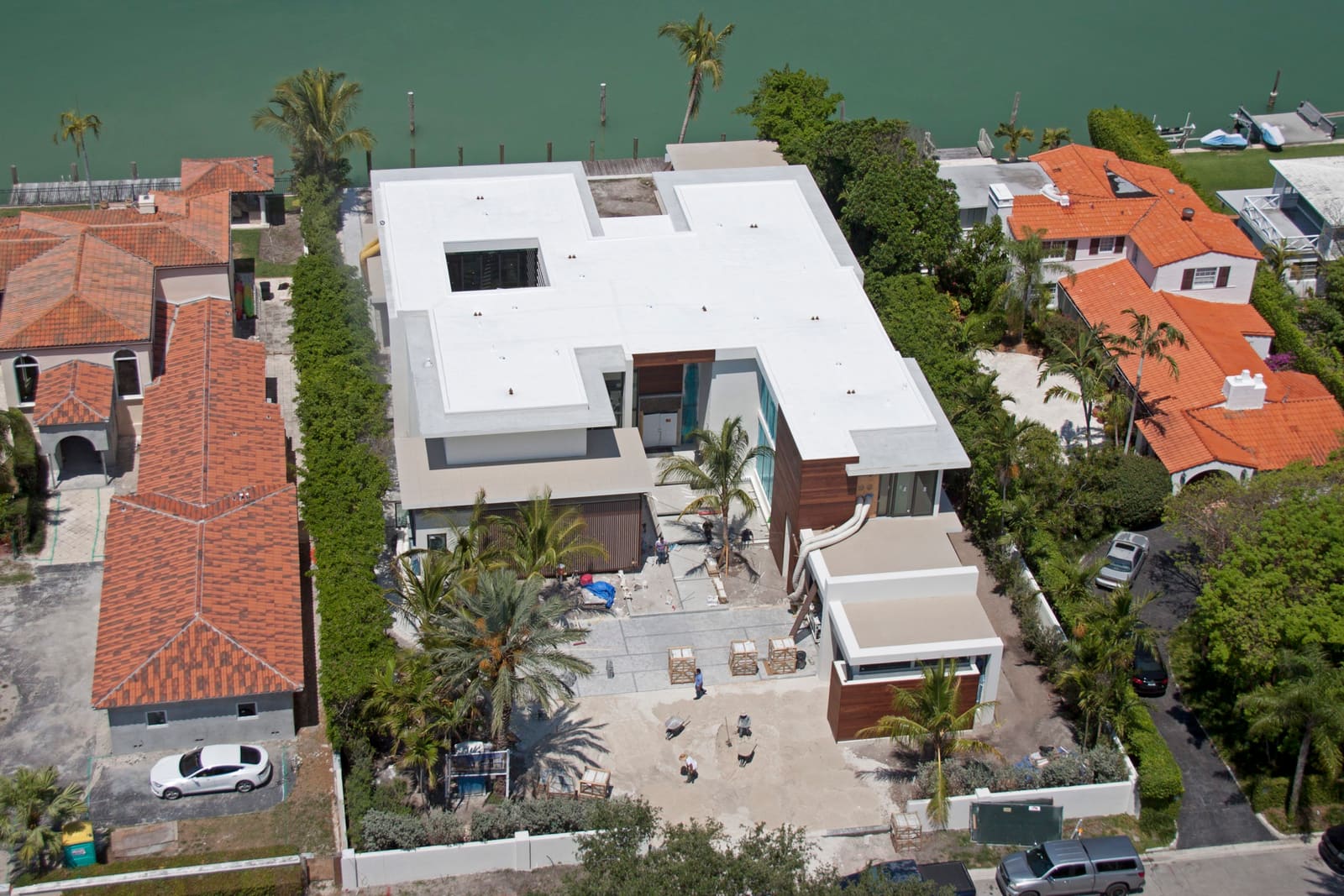 Bright white flat membrane roof on a contemporary Miami Beach waterfront home, aerial view.