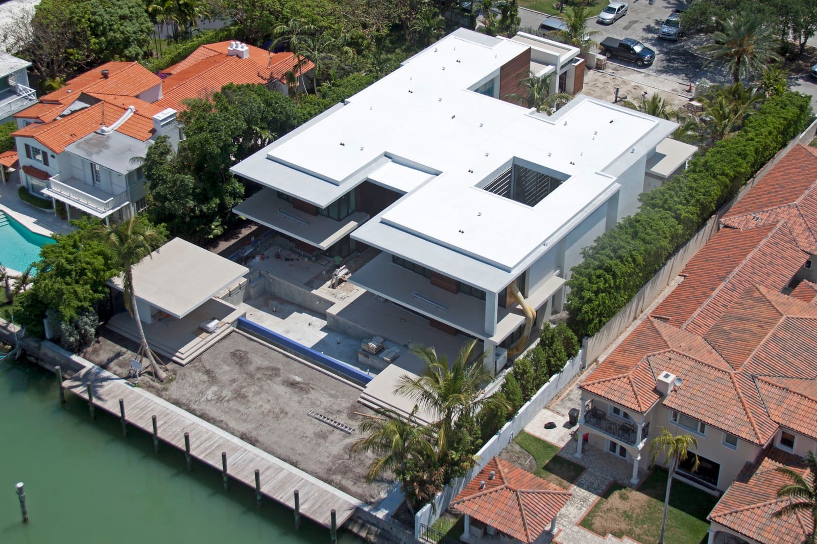 Luxury South Florida home with white flat roof, parapet walls, and tropical landscaping.