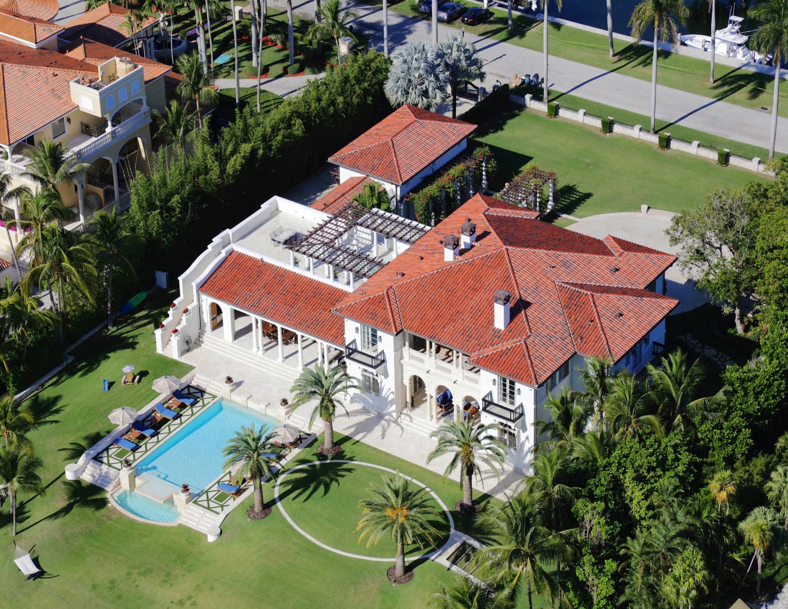 Luxury South Florida home with tile roofing, Mediterranean revival architecture, mature palm landscaping.