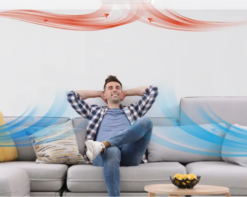 A homeowner relaxing on the couch in a cooler, well-ventilated home.