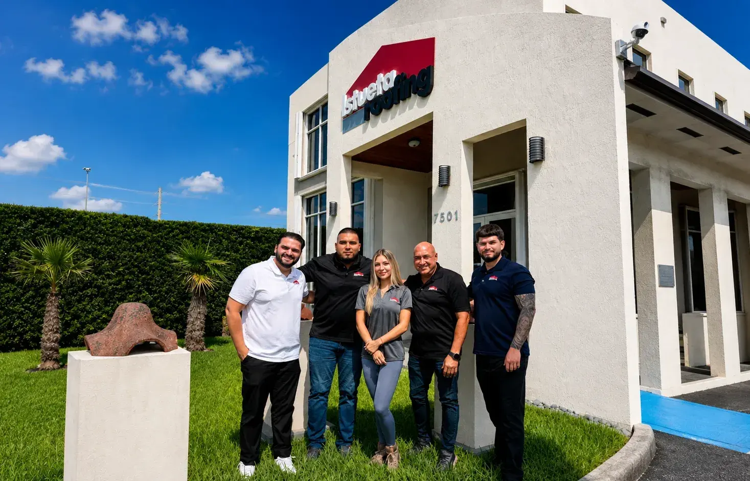 Five Istueta Roofing team members in branded polos outside the company office in Miami