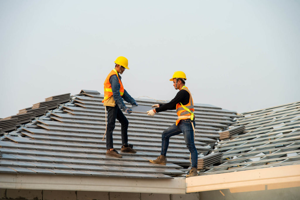 Two workers installing clay tile roof