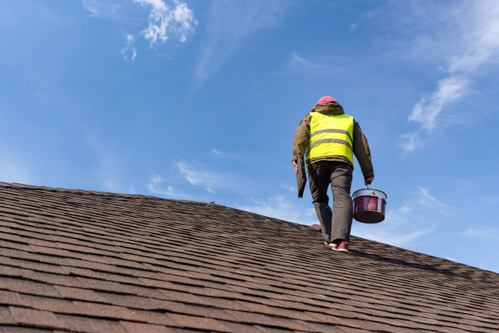 Roof repair worker on asphalt shingle roof