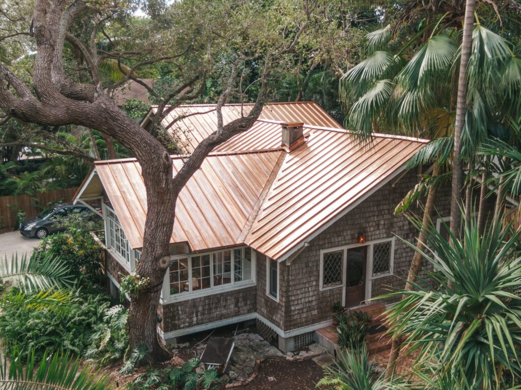 Older house in woods with shiny new copper roof