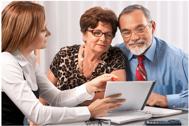Professional woman showing an older couple some information on a notebook